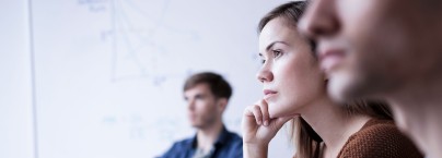 3 Personen sitzen in einm Besprechungsraum schauen konzentriert nach vorne