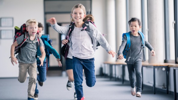 Kinder rennen glücklich durch ein Schulgebäude