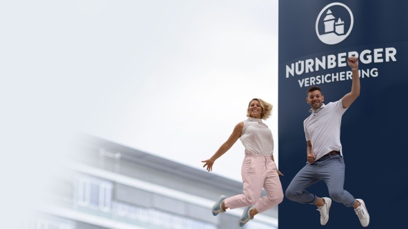 Mann und Frau springen vor dem Logo der NÜRNBERGER Versicherung in die Luft