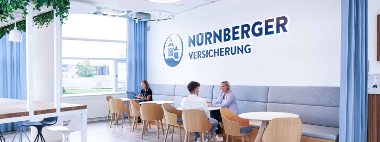 3 Personen sitzen in einem offenen Besprechungsbereich der NÜRNBERGER Versicherung
