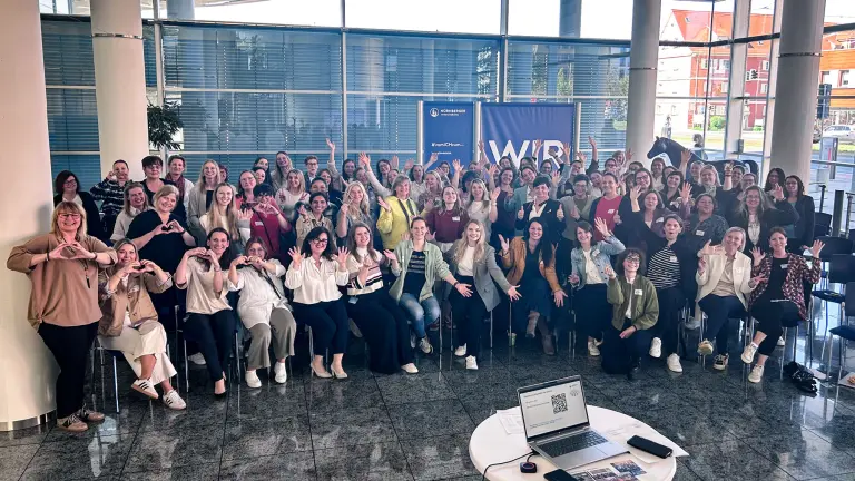 winkende Gruppe von Frauen in einer Firmenhalle