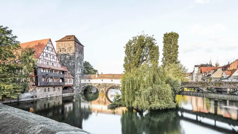 Blick auf Fluss und eine alte Steinbrücke in Nürnberg