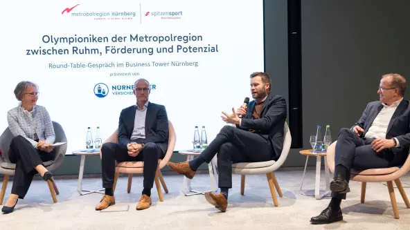 3 Männer und eine Frau sitzen für ein Roundtable-Gespräch nebeneinander