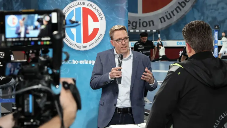 Mann mit Brille wird vor einer TV-Kamera interviewt