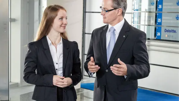 Junge Frau und älterer Mann in Business-Kleidung unterhalten sich