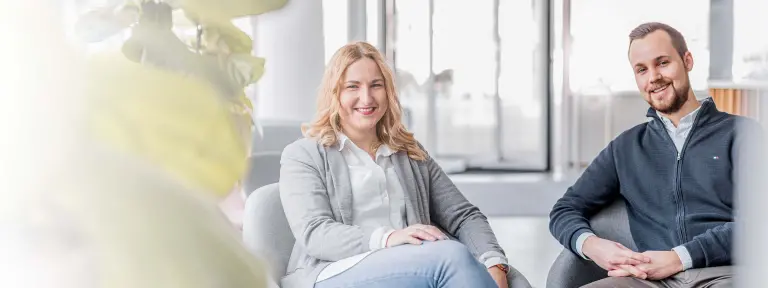 Junger Mann und junge Frau sitzen lachend nebeneinander