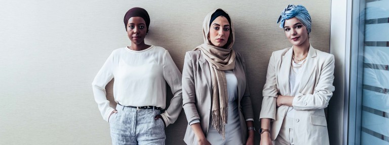 3 junge Frauen unterschiedlicher Kulturen blicken in die Kamera
