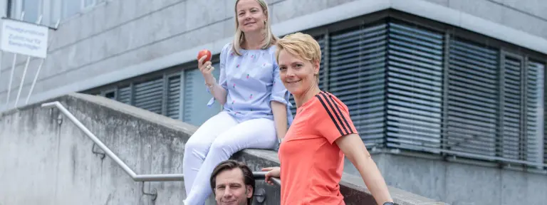 2 junge Menschen sind auf einer Treppe und schauen in die Kamera