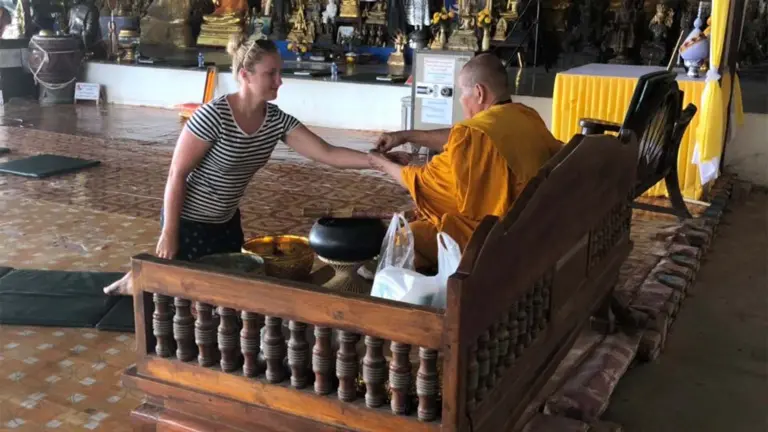 Junge Frau kniet vor einem buddhistischen Mönch