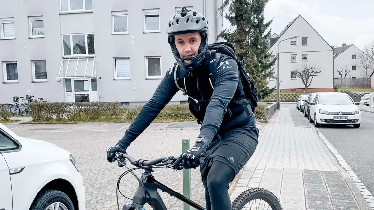 Mann fährt auf Fahrrad durch Straßenverkehr
