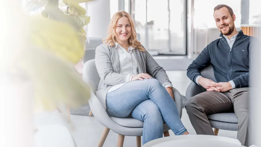 Junger Mann und junge Frau sitzen lachend nebeneinander